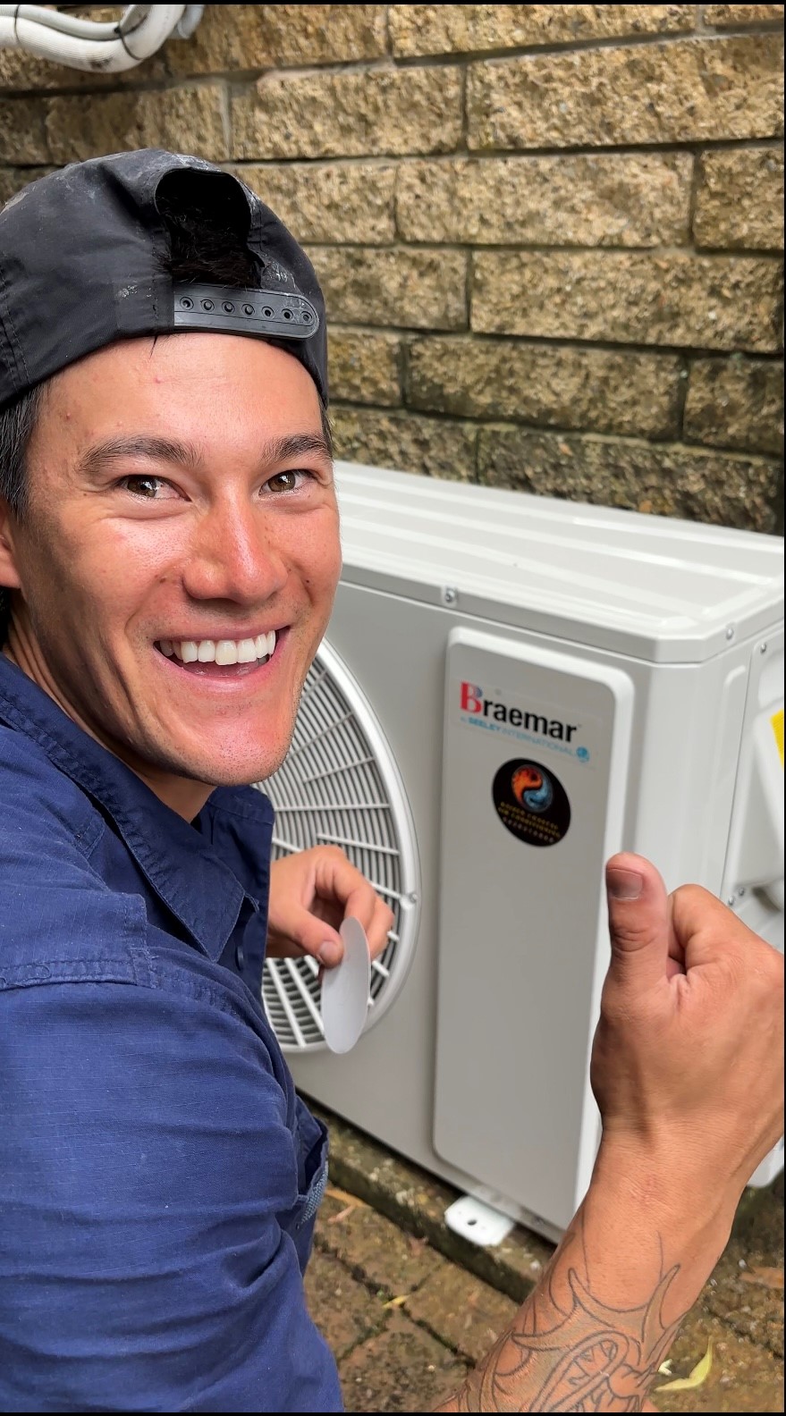 Kai Vincent smiling and giving a thumbs up beside a newly installed outdoor unit