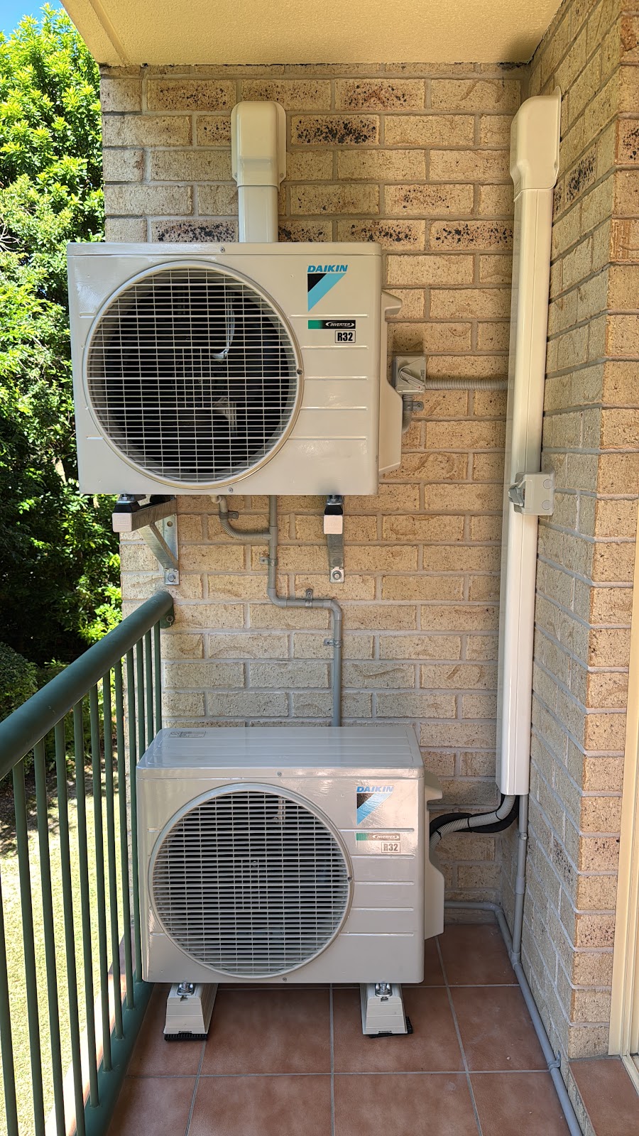 Balcony install of two stacked Daikin outdoor units seen from the side